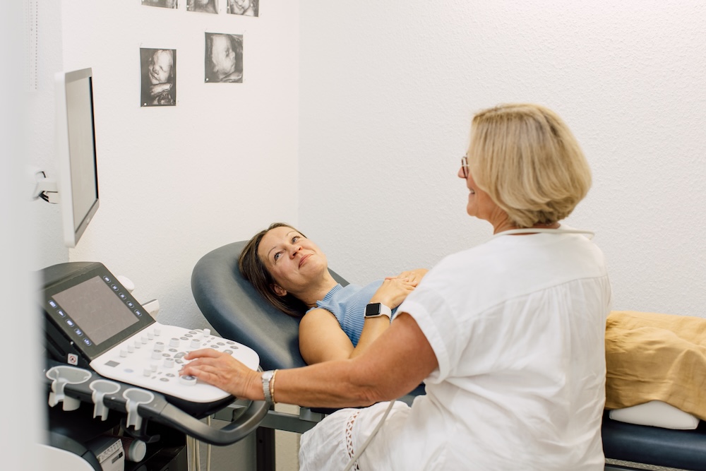 gynaekologie-trier-zita-kovaks-ultraschalluntersuchungen Ärztin im Gespräch mit einer Patientin auf der Untersuchungsliege neben dem Ultraschallgerät